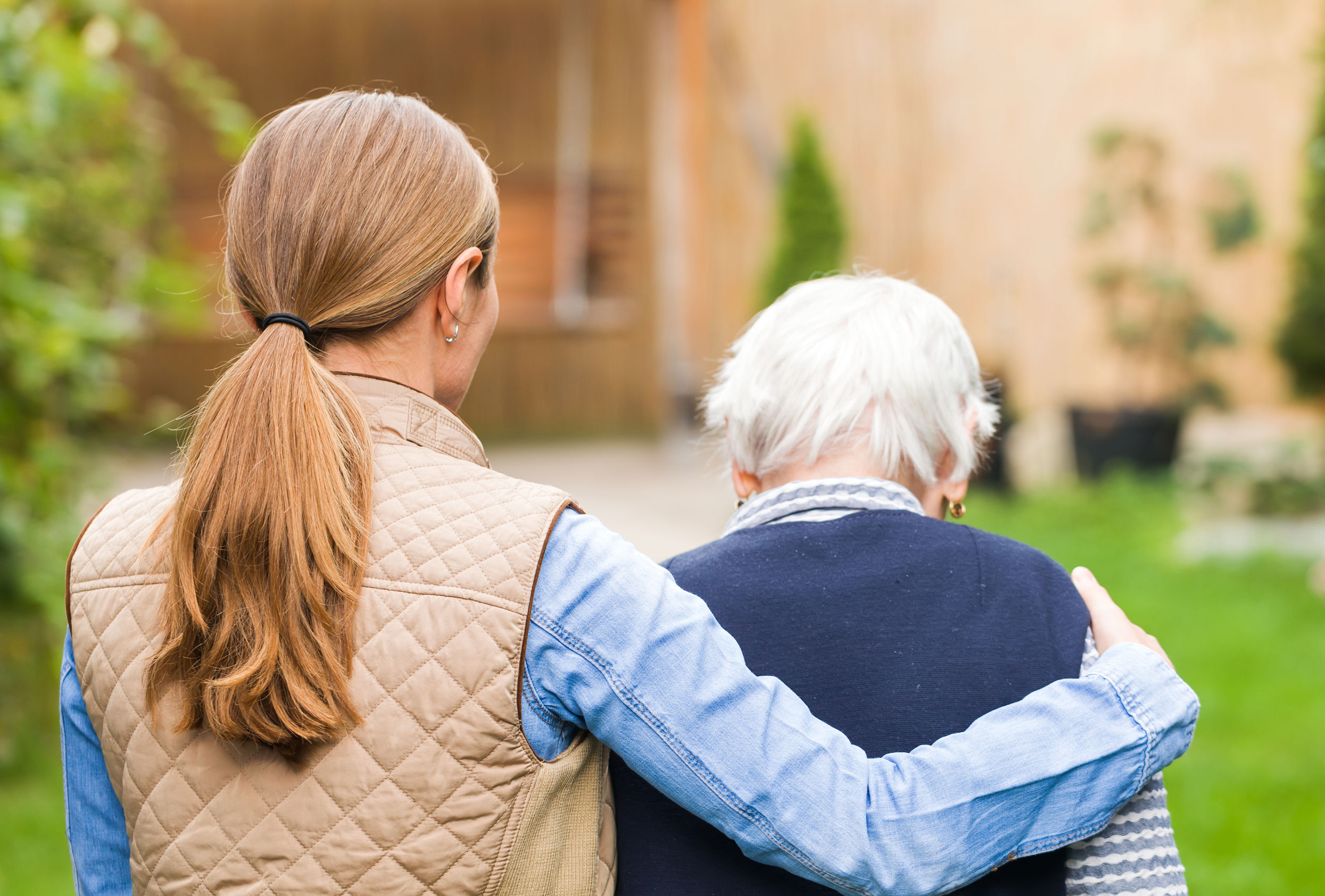 Young woman helping elderly woman to her house